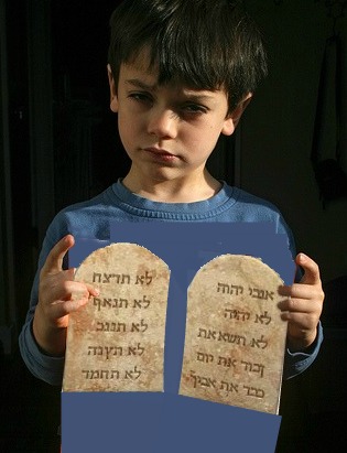 A quizzical-looking boy holds what appears to be ten commandment tablets