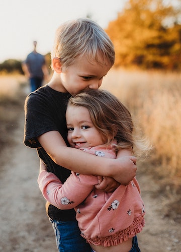A little boy hugs a little girl